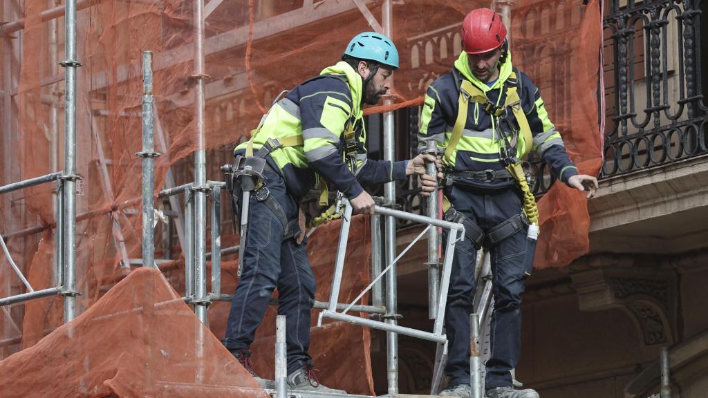 Dos trabajadores retiran un andamio en Bilbao a martes 28 de enero de 2025