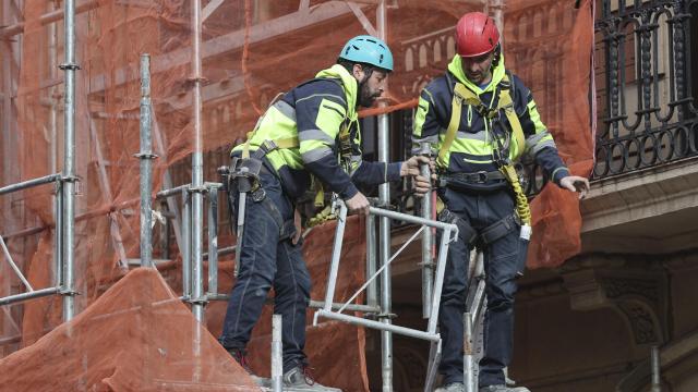 Dos trabajadores retiran un andamio en Bilbao a martes 28 de enero de 2025