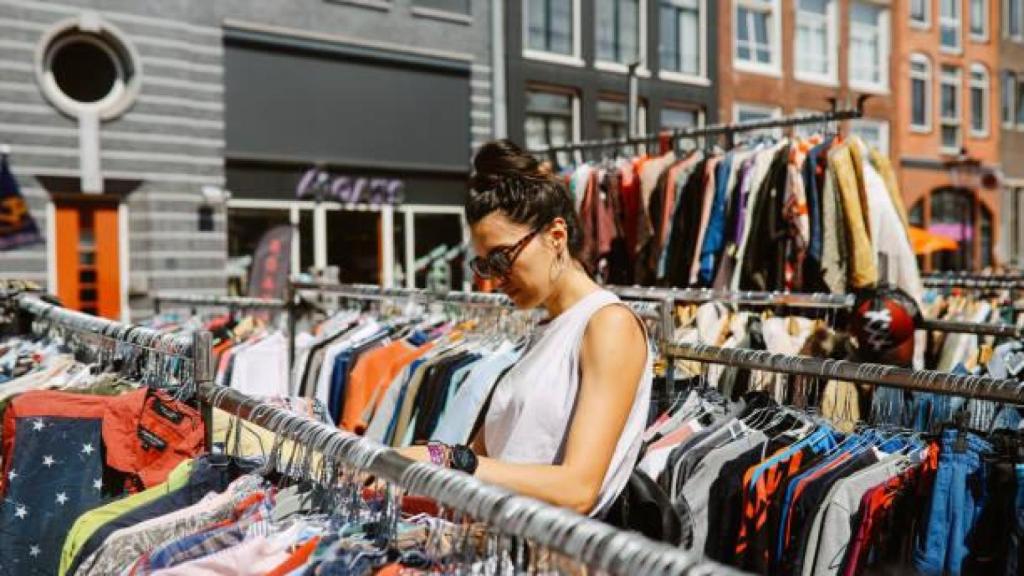 Una mujer busca ropa en un mercado al aire libre.