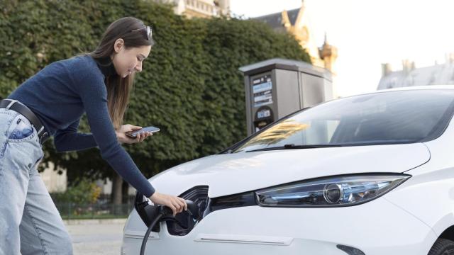 Una señora carga su coche eléctrico