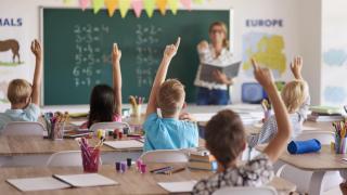 Estudiantes alzan la mano para responder.