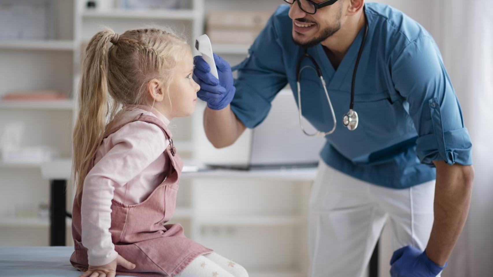 Un pediatra comprueba la temperatura corporal de una niña