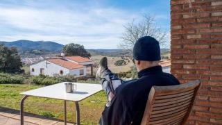 Un usuario de un alojamiento rural descansa en el porche de la casa