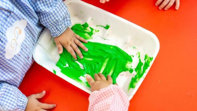 Dos niños con una bandeja de pintura en un colegio