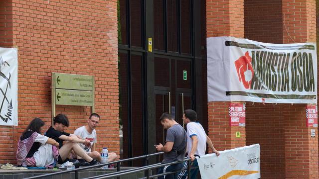 Varios jóvenes sentados este miércoles, en la entrada de la Facultad de Letras de Vitoria donde esta el recinto de las fiestas de la capital vasca con un cartel que pide la amnistía de los presos de ETA.