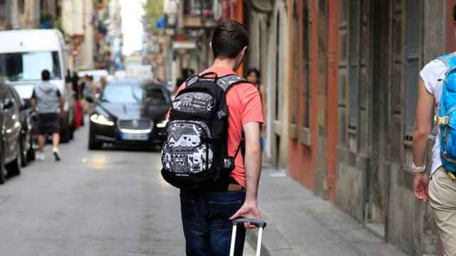 Un joven con una maleta se dirige a un piso de alquiler de temporada en Barcelona