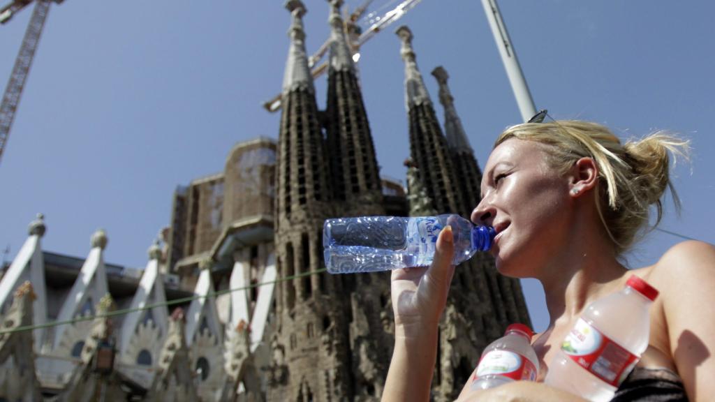 Una turista bebe agua frente a la Sagrada Família de Barcelona