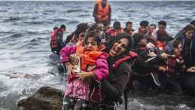 Una refugiada salta de una lancha neumática con su hija en brazos tras alcanzar la costa, en la isla de Lesbos. Octubre de 2015 / EFE/Filip Singer