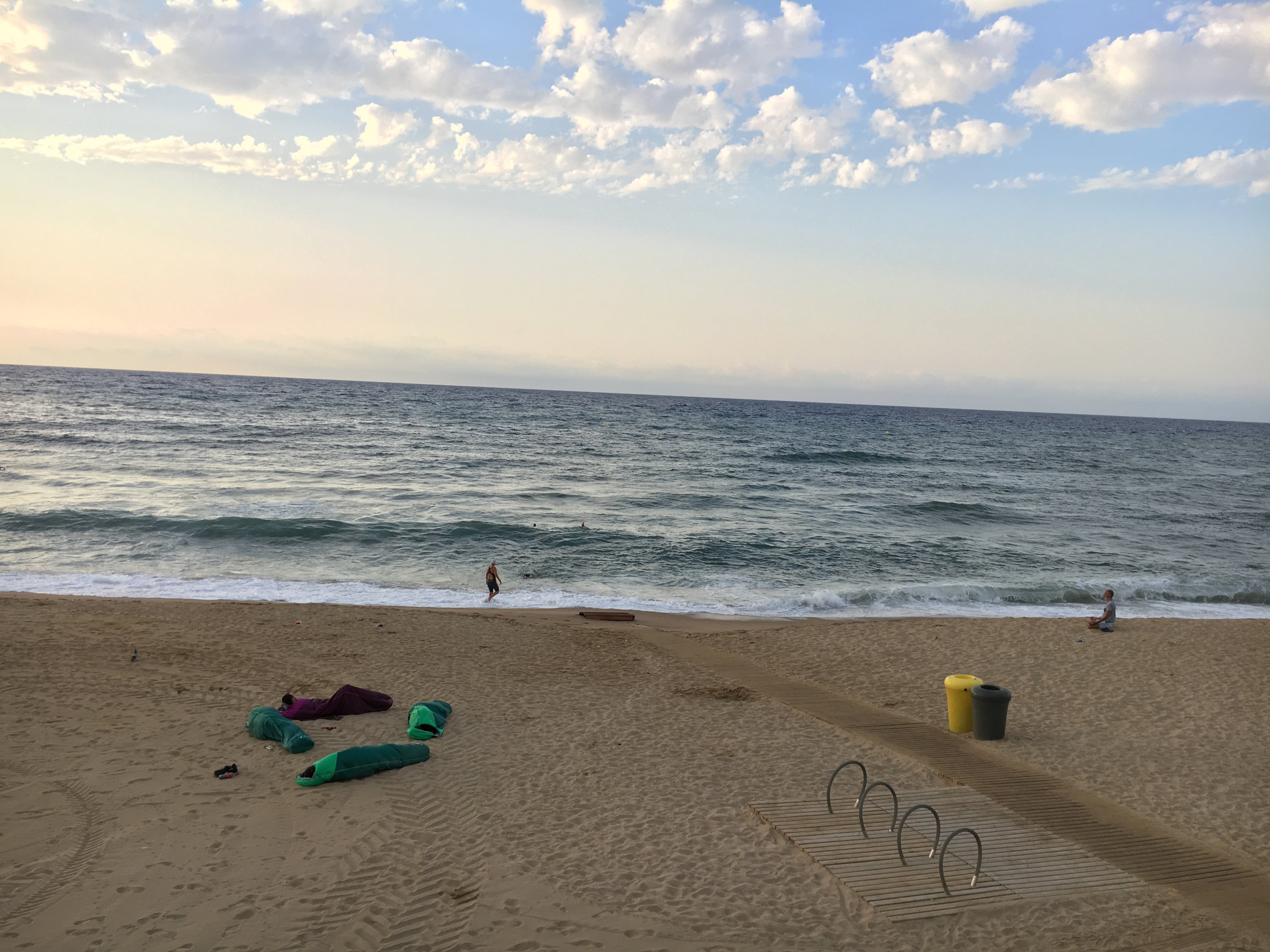 Personas que duermen en la playa de la Barceloneta con sacos de dormir