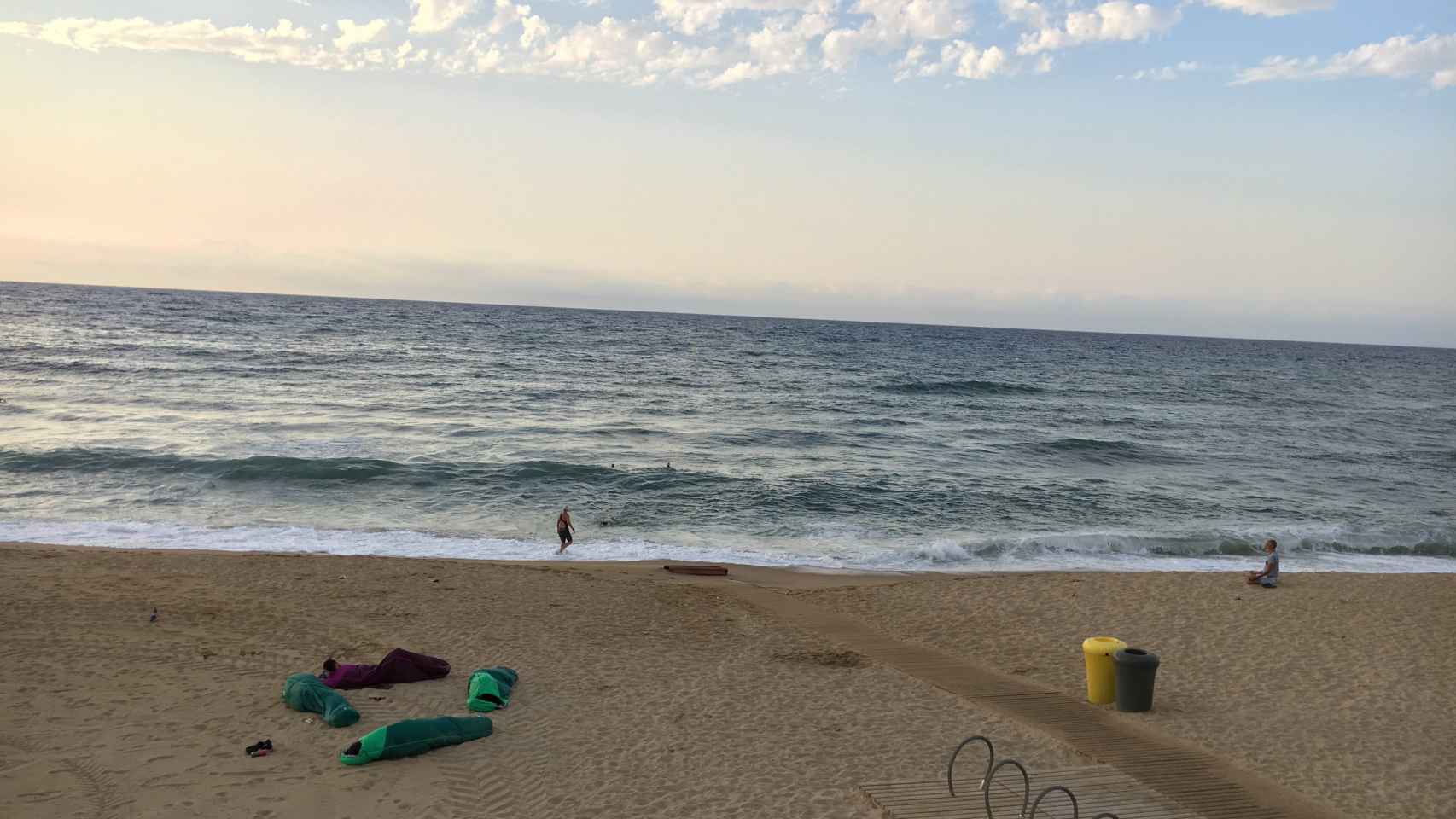 Un grupo durmiendo en sacos de dormir junto a un hombre meditando y personas practicando deporte acuático / M.S.