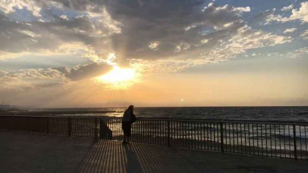 Una señora observando la Barceloneta de madrugada