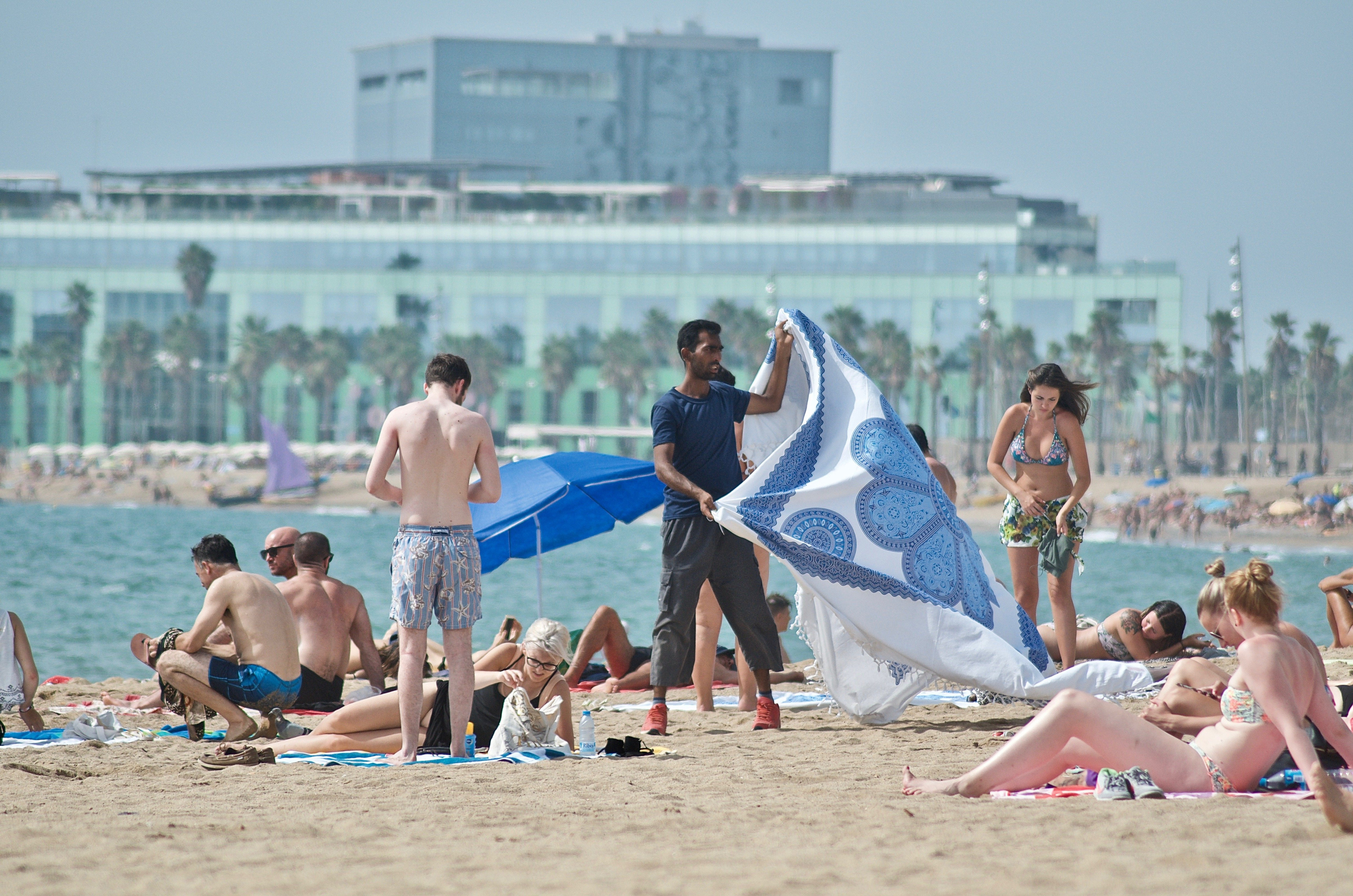 Un vendedor ambulante ofrece un pareo en la playa de Sant Miquel, en el barrio de la Barceloneta / XFDC