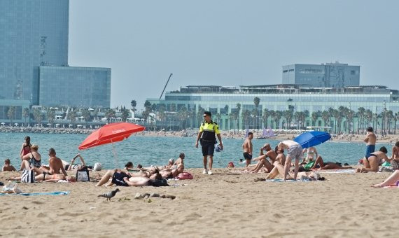 Un guardia urbana vigila la venta ambulante en la playa.