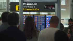 Pasajeros del Aeropuerto de Barcelona consultando los paneles de información / ARNAU MAS