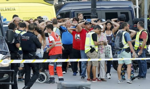 Un grupo de gente con los brazos en alto ante el despliegue policial / EFE-Andreu Dalmau