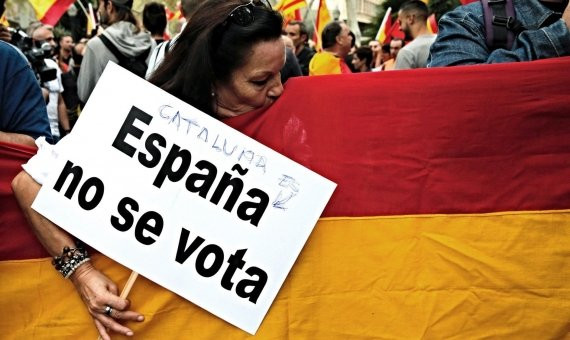 Una participante besa la bandera española durante la manifestación de plaça d'Urquinaona / EFE - Juan Carlos Cárdenas