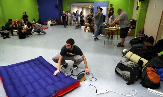 Un grupo de jóvenes se dispone a preparar colchonetas y demás útiles para dormir en las instalaciones de la Escuela Jaume I / EFE - TONI ALBIR