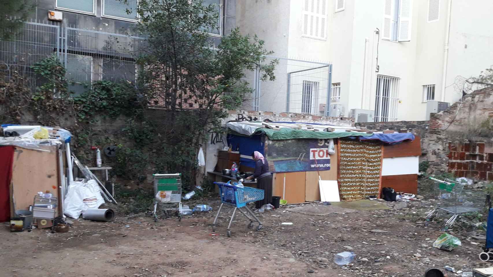 Una mujer cocina junto a unas chabolas en la calle de Lluçanès, en el Distrito de Sarrià-Sant Gervasi, en la zona alta de Barcelona / DAVID BIGORRA