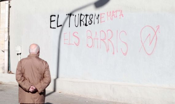 Un anciano mira la pintada contra el turismo / ÁLVARO VENTURA