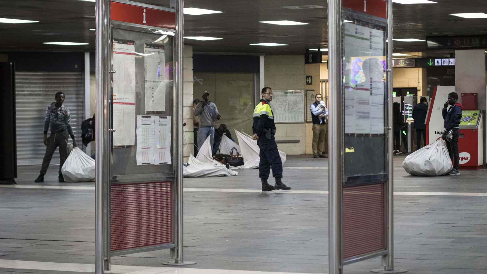 Manteros en la estación de Plaza Catalunya, vigilados por un Mosso d'Esquadra / HUGO FERNÁNDEZ