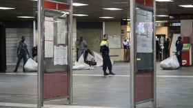 Manteros en la estación de Plaza Catalunya, vigilados por un Mosso d'Esquadra / HUGO FERNÁNDEZ