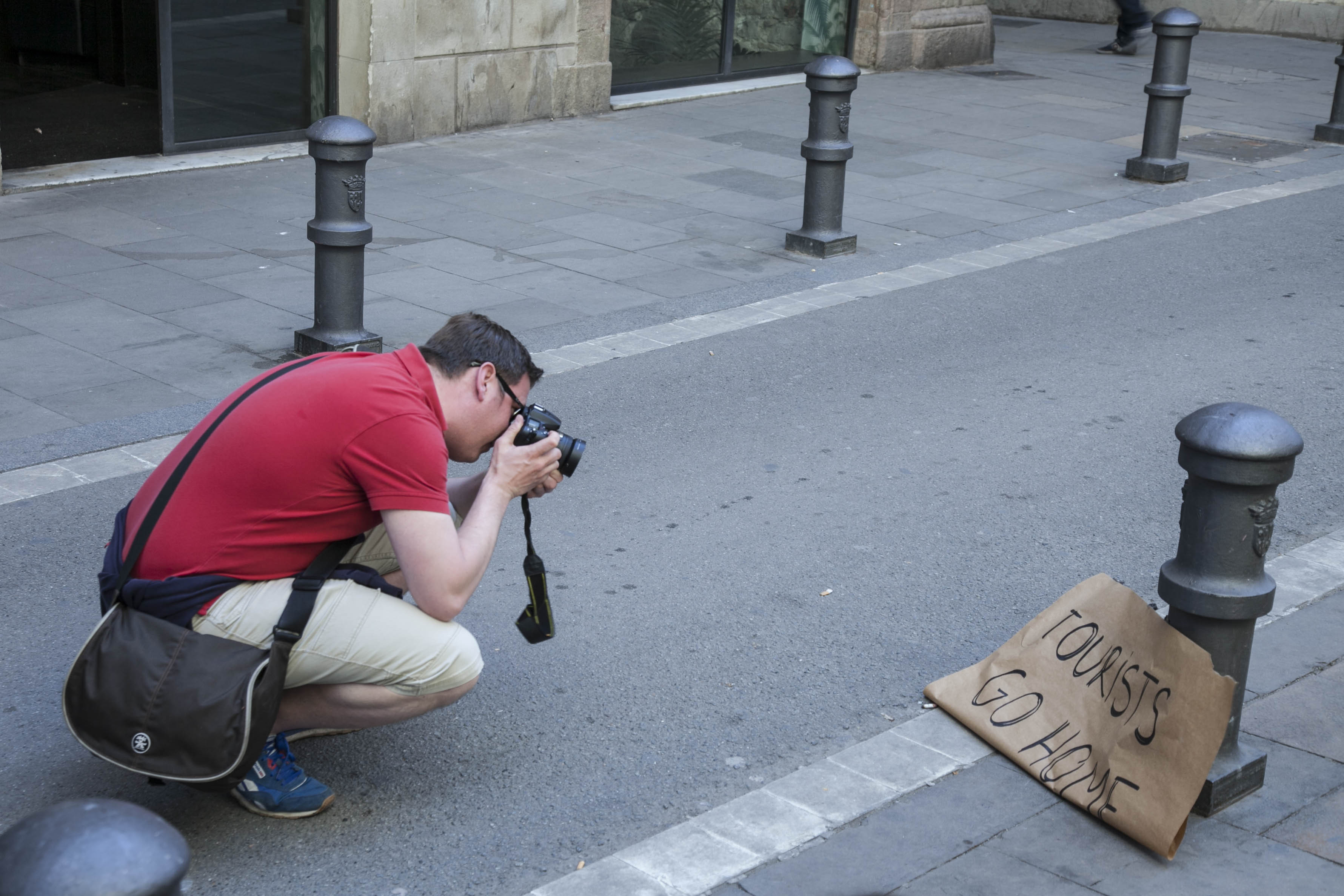 Un turista fotografía un cartel contrario a la llegada de turistas a Barcelona / ÁLVARO VENTURA