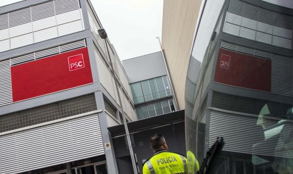 Un guardia urbano observa la sede del PSC del Poblenou / ÁLVARO VENTURA