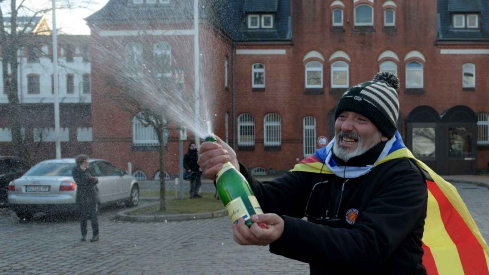 Un hombre con una 'estelada' celebra con champán la futura libertad de Carles Puigdemont frente a la cárcel de Neumünster, donde permanece recluido el expresidente catalán / EFE