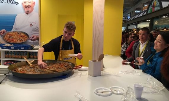 Un cocinero sirve paella a una visitante oriental en Alimentaria / MIKI