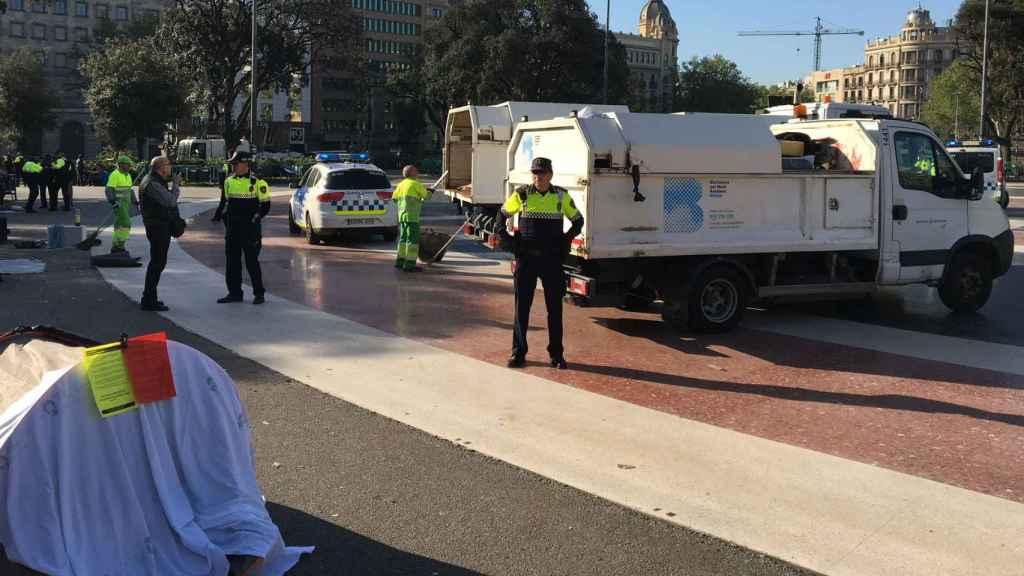 Agentes de la Guàrdia Urbana y camiones de la basura durante el desalojo de la acampada de sin techo de plaza de Catalunya en aplicación de la Ordenanza de civismo