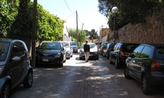 Kelly Arrontes caminando por su calle con los coches mal aparcados 