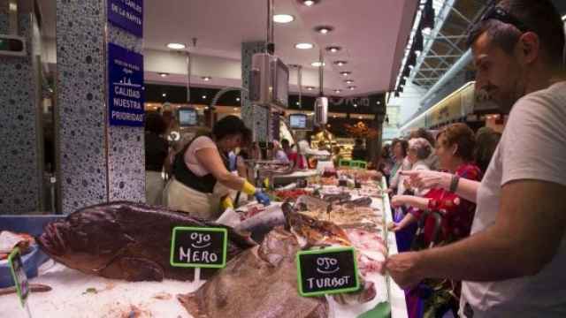 Distintos clientes compran en una parada de pescado de Sant Antoni