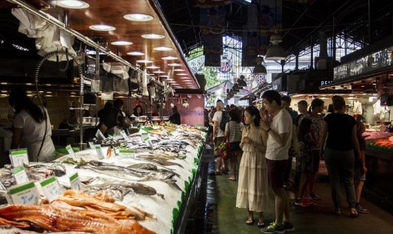 Turistas asiáticos mirando el pescado en La Boqueria | HUGO FERNÁNDEZ