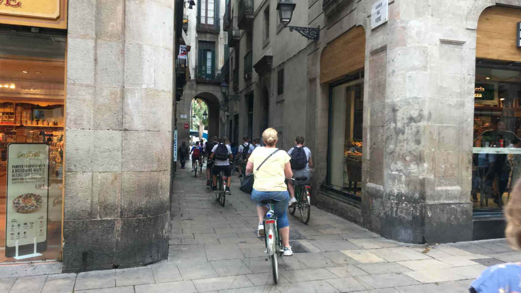 Turistas en bici por la calle del Vidre