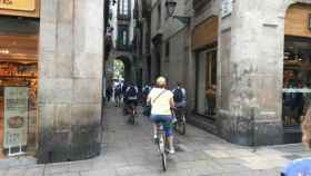 Turistas en bici por la calle del Vidre