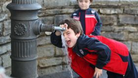 Dos niños pequeños bebiendo agua de una fuente en Barcelona