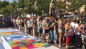 Algunos asistentes a la procesión optan por pasar por encima de las prendas que venden los manteros.