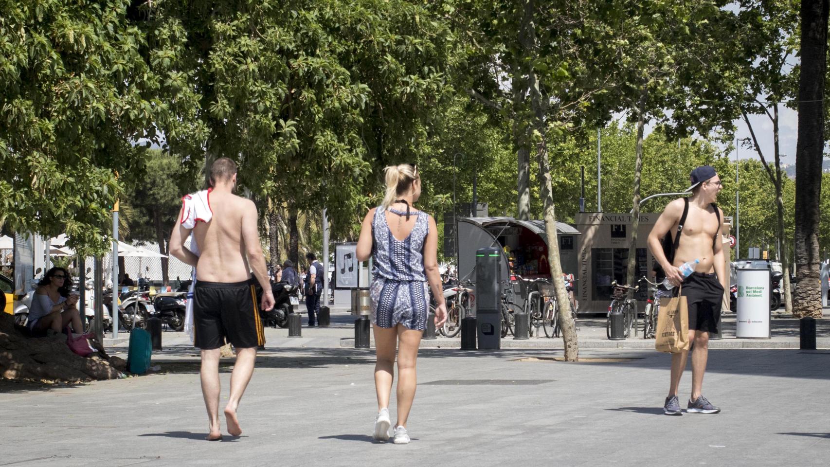 Turistas sin camiseta paseando por la Barceloneta, por el fuerte calor de Barcelona