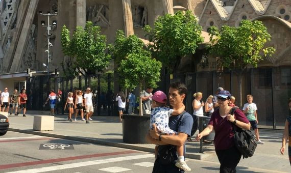 Un padre carga con su hijo tras visitar la Sagrada Familia / MIKI