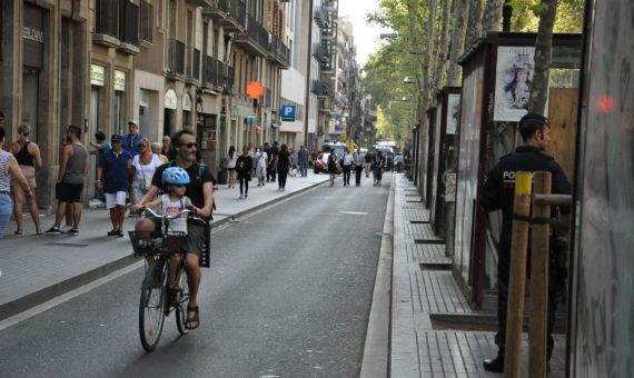 Un padre pasea a su hijo en bici bajo la mirada de un policía / MIKI