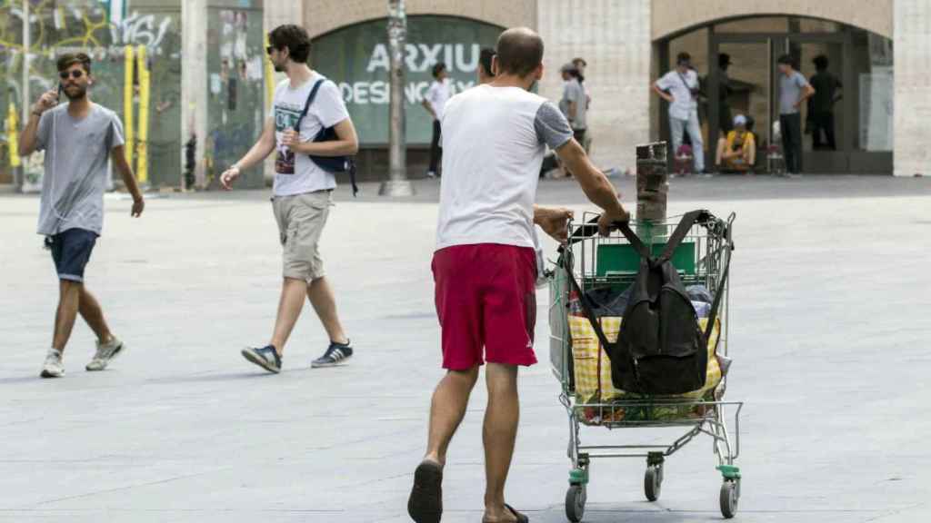 Hombre recogiendo chatarra se cruza con turistas / HUGO FERNÁNDEZ