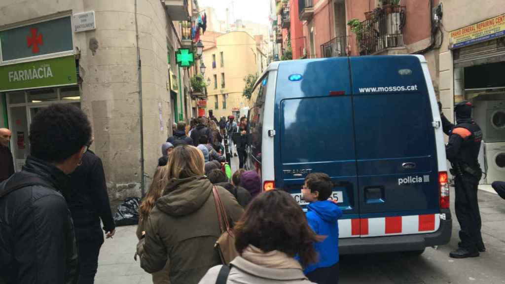 Un grupo de niños pasa al lado de una furgoneta policial durante el operativo / HUGO FERNÁNDEZ