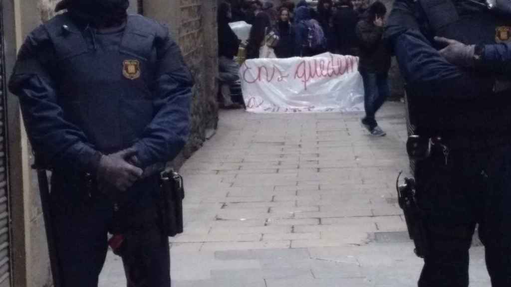 Vecinos del Gòtic se manifiestan frente al edificio ocupado detrás de agentes policiales / TWITTER