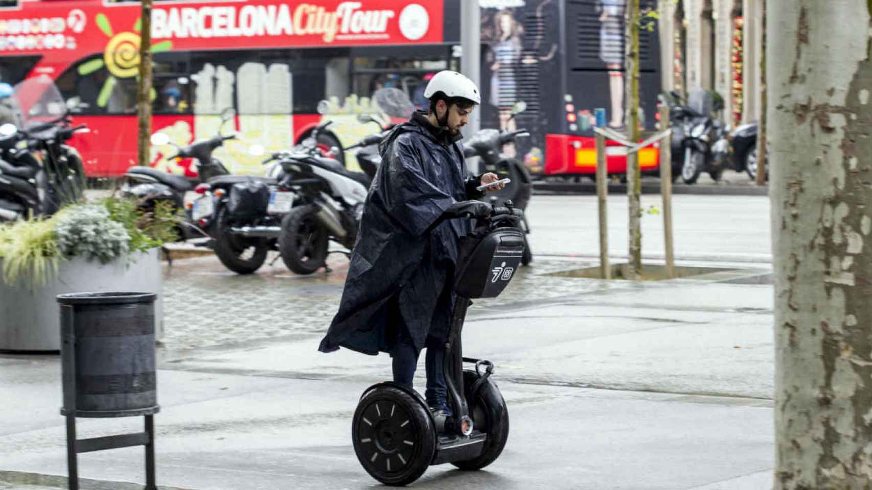 En Segway, bajo la lluvia, por la acera y mirando el móvil.