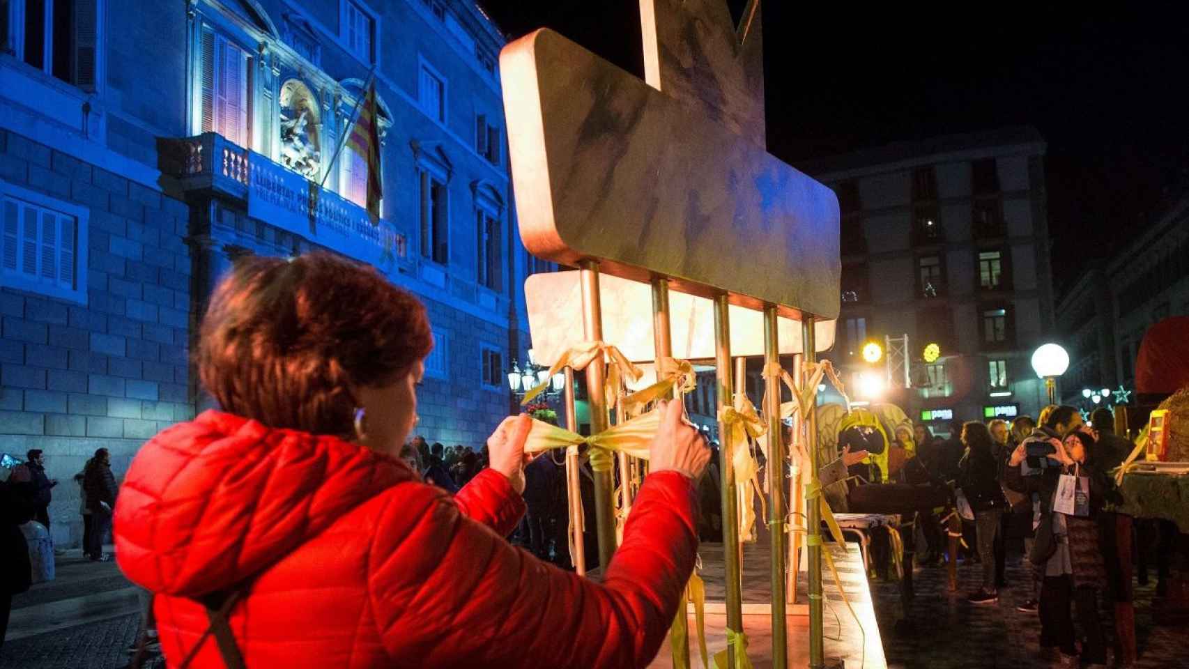 Una manifestante, colocando lazos amarillos en el pesebre / EFE