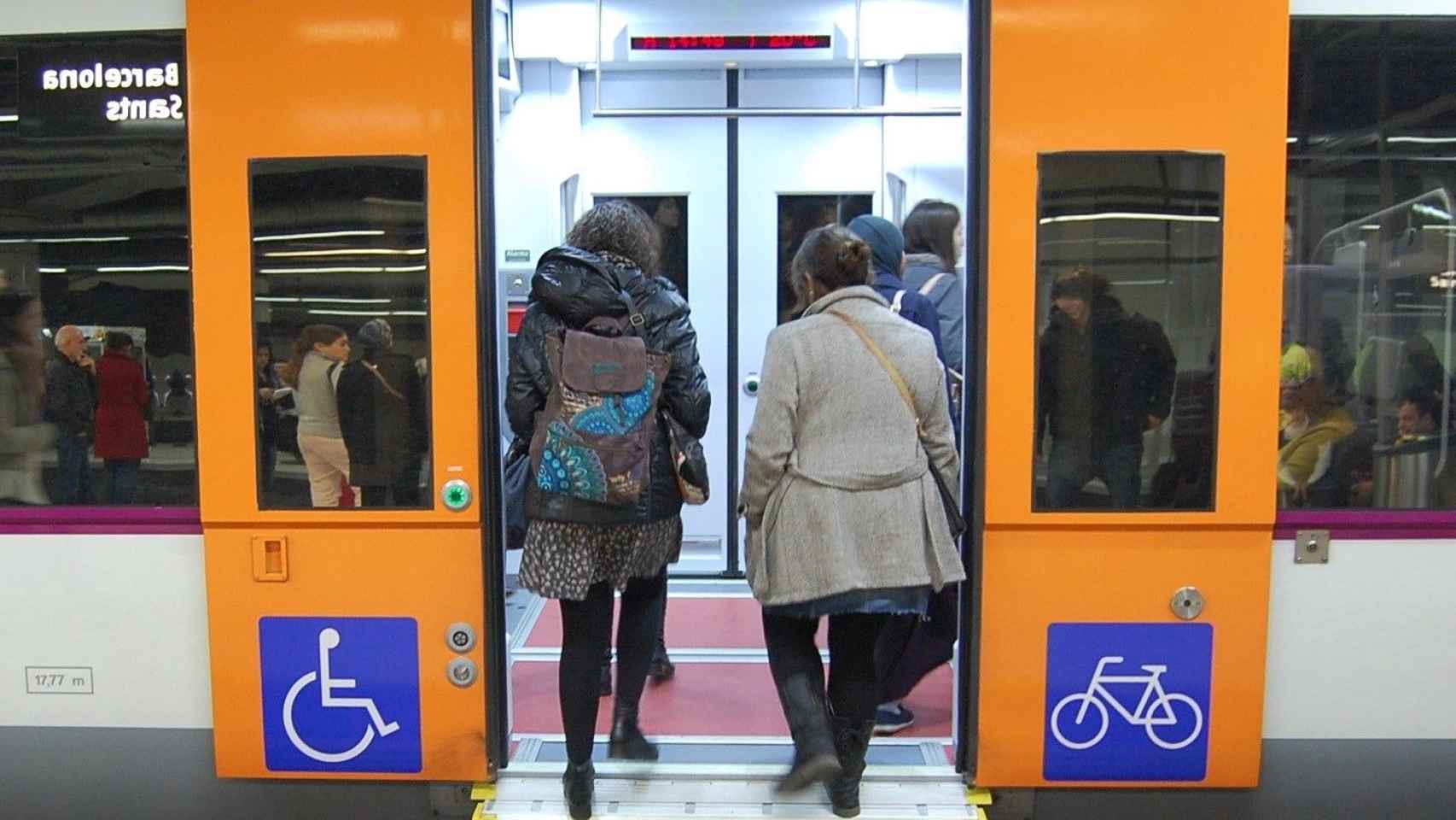 Dos personas accediendo a un convoy de Rodalies