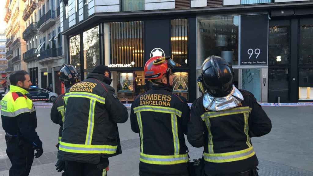 Bomberos de Barcelona observan la fachada del edificio que ha sufrido un desprendimiento en paseo de Gràcia / PABLO ALEGRE