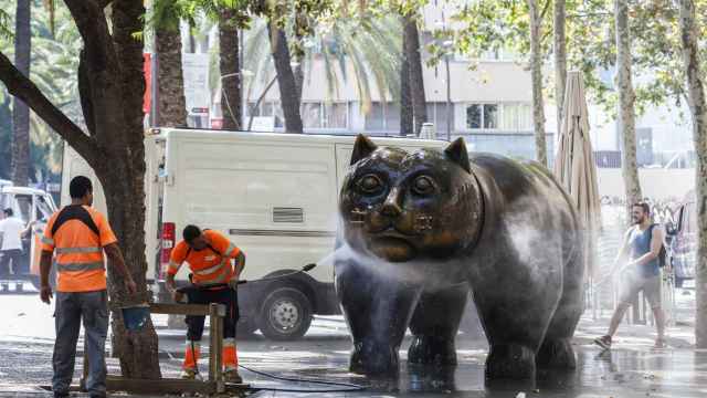 Personal de limpieza usando una manguera para limpiar el gato de Botero de la Rambla Raval / HUGO FERNÁNDEZ