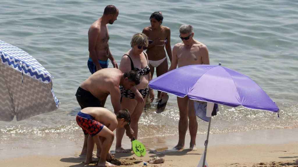 Bañistas de la Playa de la Barceloneta contemplan una medusa / HUGO FERNÁNDEZ