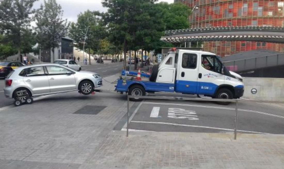 Una grúa municipal entra con un coche enganchado en el depósito de Glòries / JORDI SUBIRANA